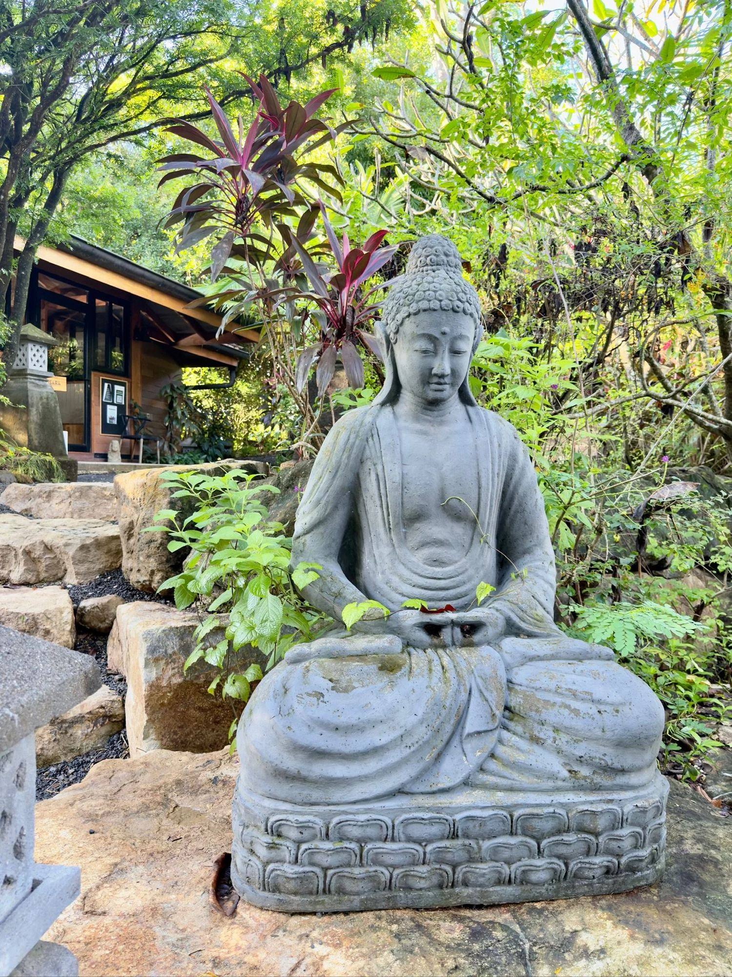 A stone Buddha among tropical plants at Bodhi Tree