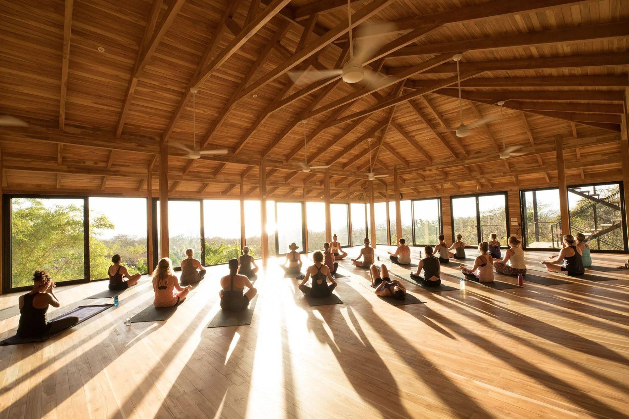 An open-air yoga shala at Bodhi Tree in Nosara with students practicing at golden hour