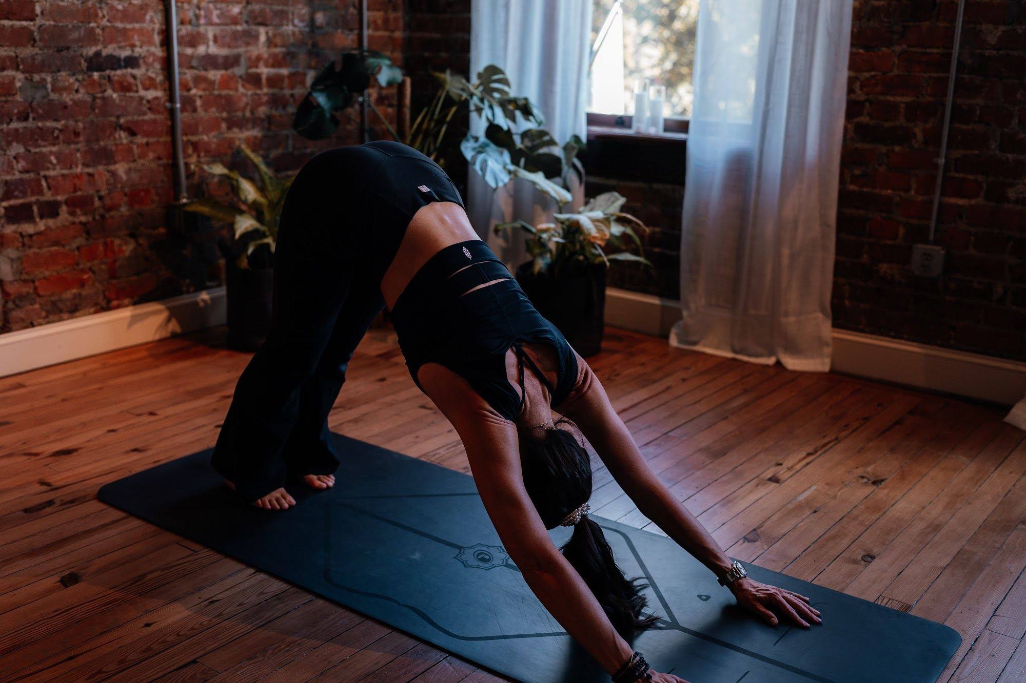 A student in downward dog in warm, low light